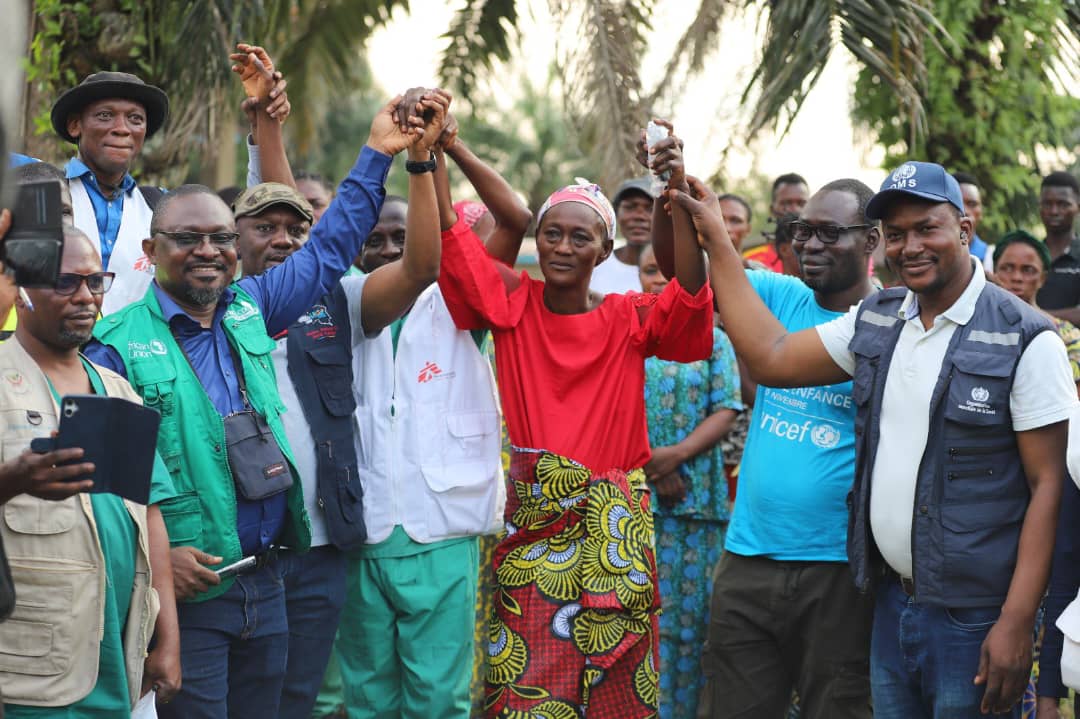 Health workers and partners raise the hands of an Ebola survivor in celebration, as two patients are discharged from the Bulape treatment centre in Kasai Province, DR Congo. Credit: WHO